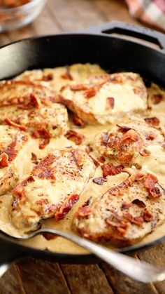 a skillet filled with meat and cheese covered in sauce on top of a wooden table