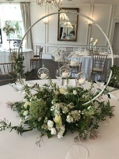 an arrangement of flowers and greenery on a table at a wedding reception in a banquet hall