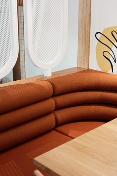 an orange couch sitting on top of a wooden table next to two large white speakers