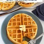 a waffle on a plate with butter next to other plates and utensils