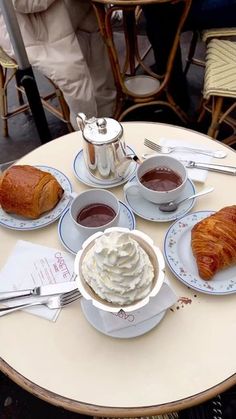 there is a croissant, cup of coffee and other food on the table