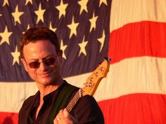 a man with sunglasses on holding a guitar in front of an american flag wallpaper