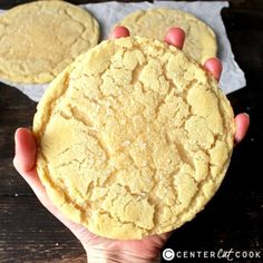 a person holding up two cookies on top of a wooden table