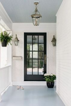 a black front door with two potted plants next to it