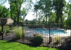 a fenced in pool surrounded by lush green grass