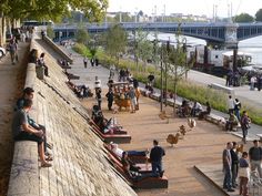 many people are sitting on benches near the water