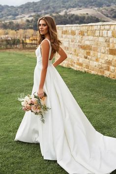 a woman in a wedding dress standing on the grass