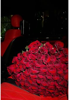 a large bouquet of red roses sitting in the back seat of a car on display