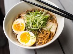 a white bowl filled with noodles, meat and eggs