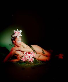 a woman laying on the ground with flowers in her hair and wearing a hula skirt