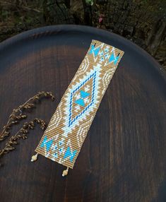 a beaded bracelet sitting on top of a wooden table next to dried flowers and plants