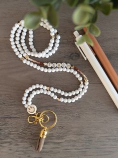 a white beaded necklace with gold accents and a pair of scissors next to it