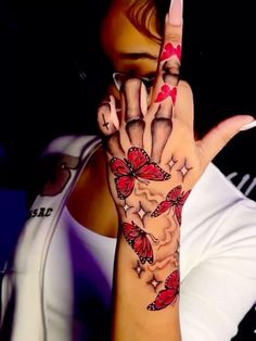 a woman is holding her hand up to show the peace sign with butterflies on it