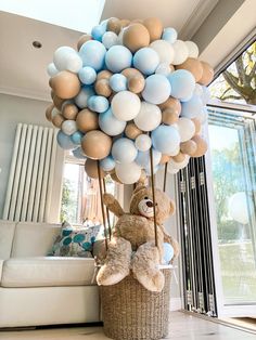 a teddy bear sitting on top of a basket filled with balloons