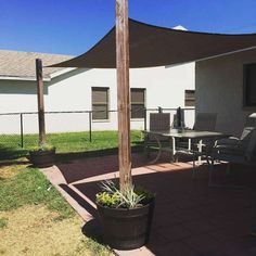 an outside patio with a table and chairs under a large shade sail on the roof