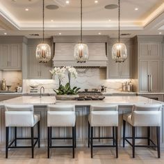 a kitchen island with four stools in front of it and lights hanging from the ceiling