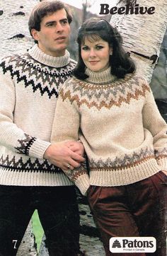 two people standing next to each other wearing sweaters