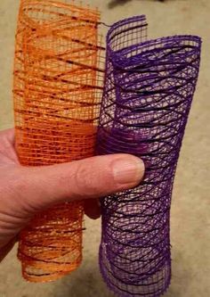 two orange and one purple pieces of wire wrapped in mesh are held up to the camera