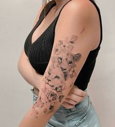 a woman with a lion and flowers tattoo on her arm is posing for the camera