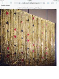 a gold curtain with red and black hearts hanging from it's side in front of a wall