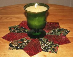 a green candle sitting on top of a table next to a red and black napkin