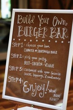 a chalkboard sign with instructions for burgers and drinks on it in front of a wooden table