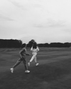 two people running across a field with a frisbee in the air above them