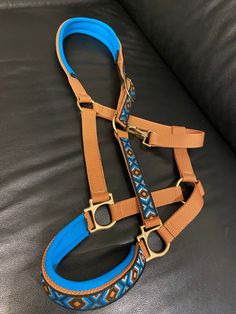 a blue and brown dog harness sitting on top of a couch