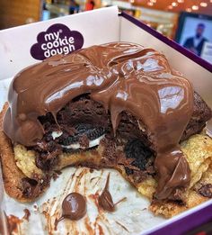 a half eaten chocolate doughnut in a box with ice cream and chocolate drizzle