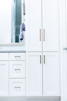 a bathroom with white cabinets and gold handles