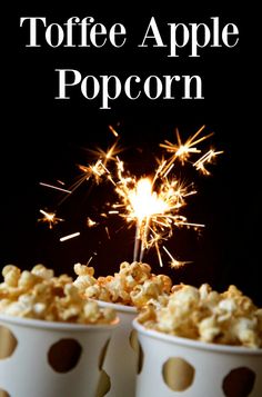 two cups filled with popcorn sitting on top of a table next to a sparkler