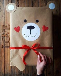 a person holding a brown paper bag with a teddy bear on it and a red ribbon