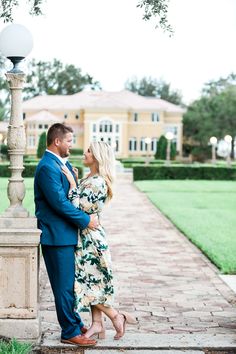 a man and woman standing next to each other in front of a light post on a brick walkway