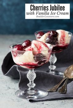 two glasses filled with ice cream and cherries on top of a cloth covered table