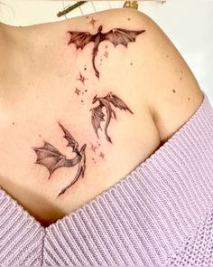 a woman's chest with two flying bats on her left shoulder and the other side