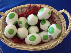 a basket filled with green and white eggs on top of a blue cloth covered table