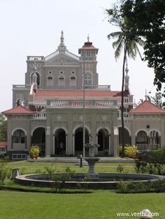 a large white building with a fountain in front of it and trees around the perimeter