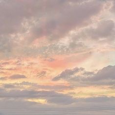 the sky is pink and cloudy with power lines in the foreground, and telephone poles in the background