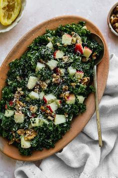 a plate filled with kale salad next to bowls of nuts