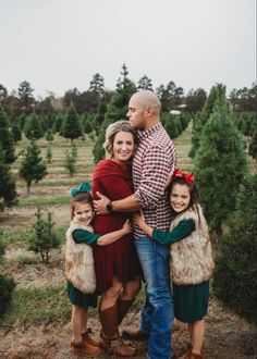 a family posing for a photo in front of christmas trees