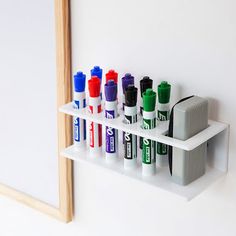 several different colored markers on a white shelf