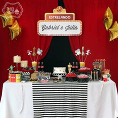 a table topped with lots of food and desserts next to a red curtained wall