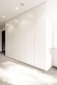 an empty room with white cupboards and carpeted flooring in the foreground