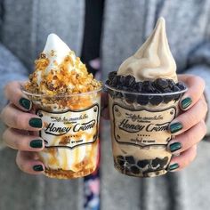 two people holding up cups with ice cream and toppings