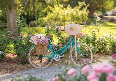 a blue bicycle with a basket full of flowers and a straw hat on the handlebars