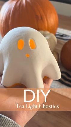 a person holding a fake ghost in front of pumpkins with text overlay that reads diy tea light ghosties