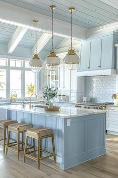 a large kitchen with blue cabinets and white counter tops, gold pendant lights over the island