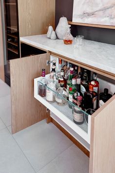 an open cabinet in a kitchen filled with bottles and condiments on the counter