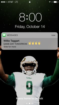 a football player holding his hands up in the air while wearing a green and white uniform