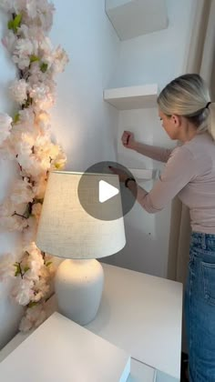 a woman standing next to a white table lamp